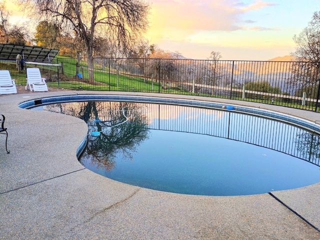 pool at dusk featuring a patio