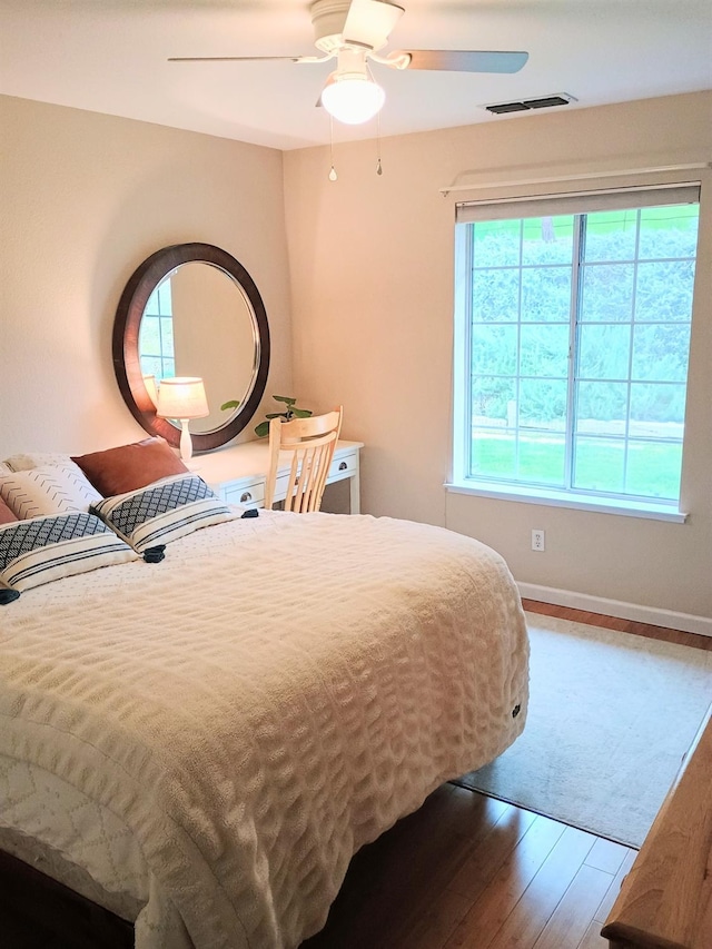 bedroom featuring visible vents, baseboards, a ceiling fan, and wood finished floors