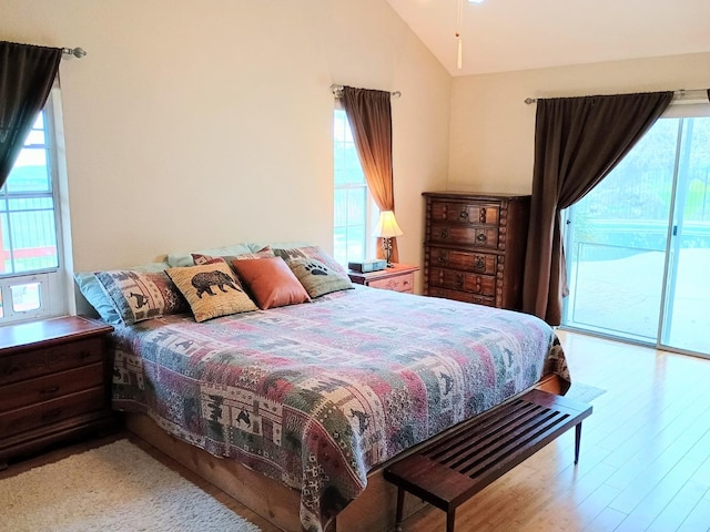 bedroom featuring lofted ceiling, access to exterior, and light hardwood / wood-style flooring