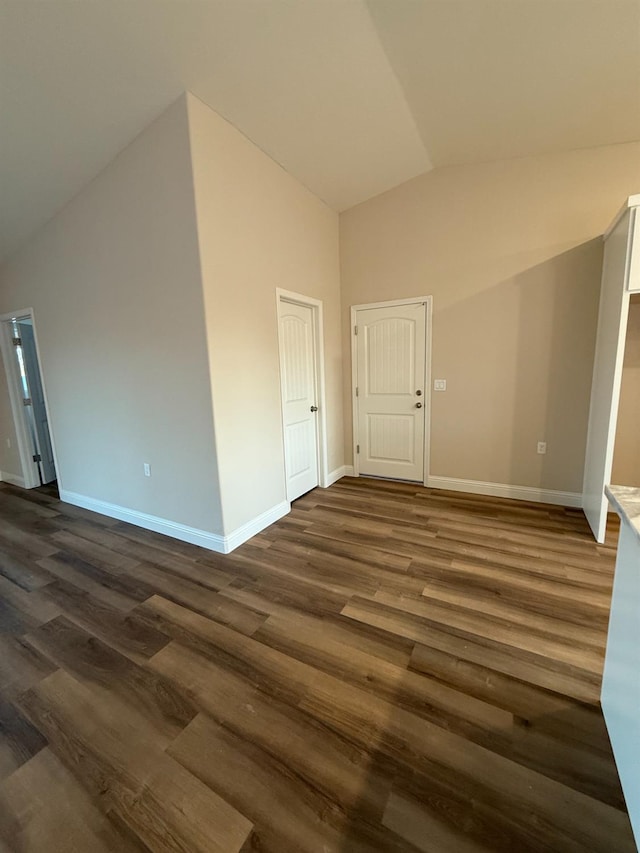 empty room with vaulted ceiling and dark hardwood / wood-style floors