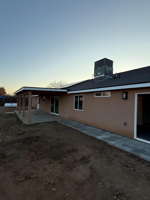 back house at dusk with a patio and central AC