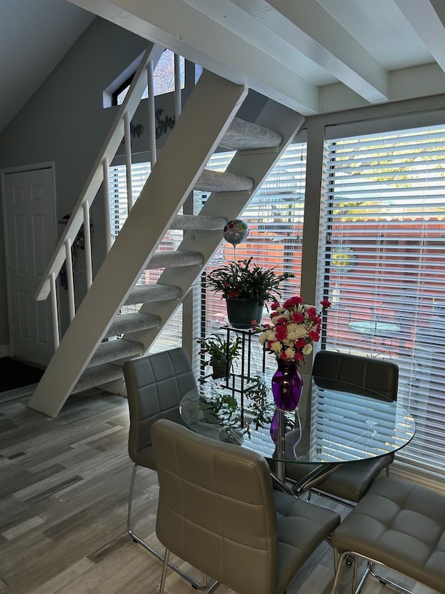 stairway with wood-type flooring and beamed ceiling