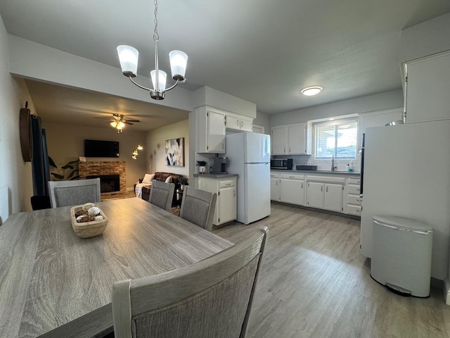 dining area featuring ceiling fan with notable chandelier, sink, and light hardwood / wood-style flooring