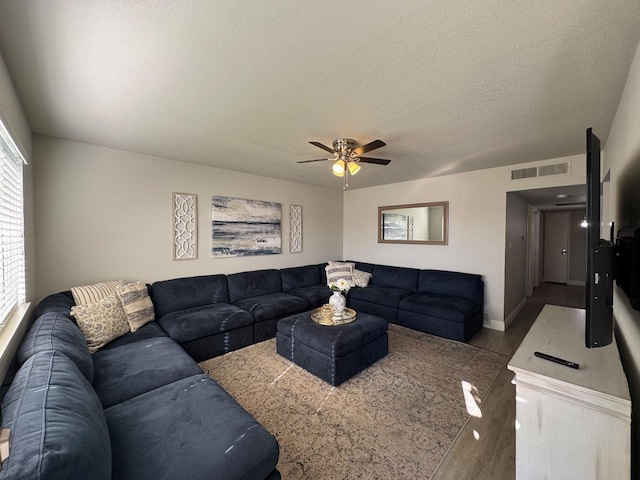 living room with light hardwood / wood-style floors, a textured ceiling, and ceiling fan