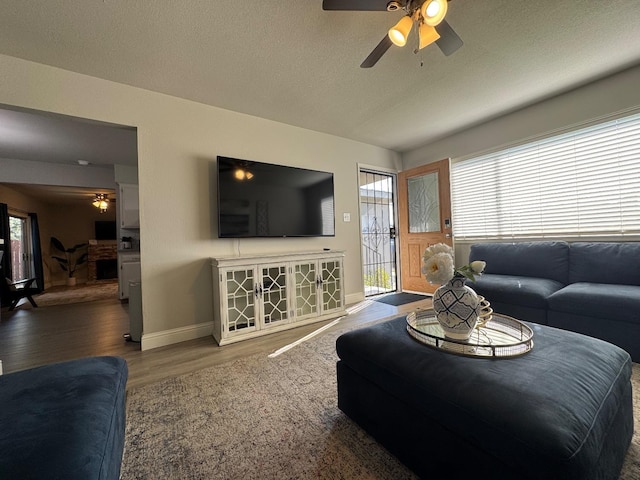 living room featuring ceiling fan, wood-type flooring, and a textured ceiling