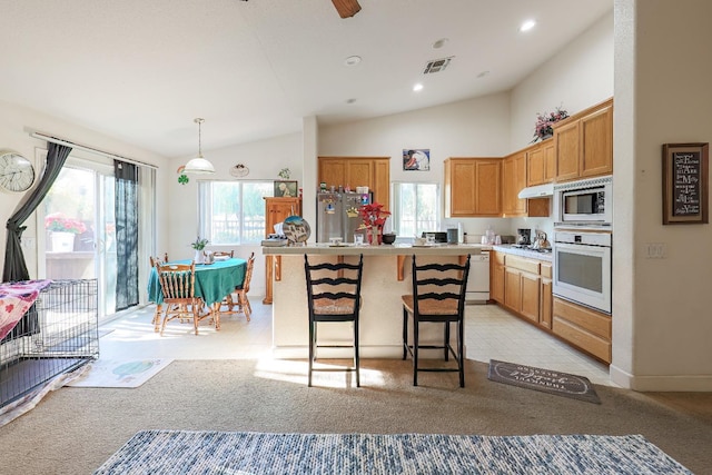 kitchen featuring light carpet, pendant lighting, a kitchen island, lofted ceiling, and stainless steel appliances