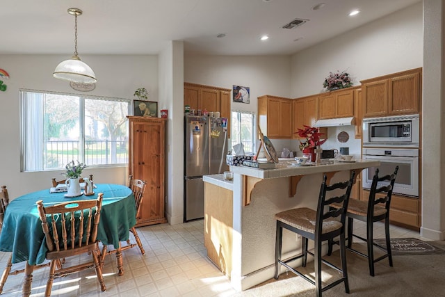 kitchen featuring decorative light fixtures, high vaulted ceiling, and appliances with stainless steel finishes