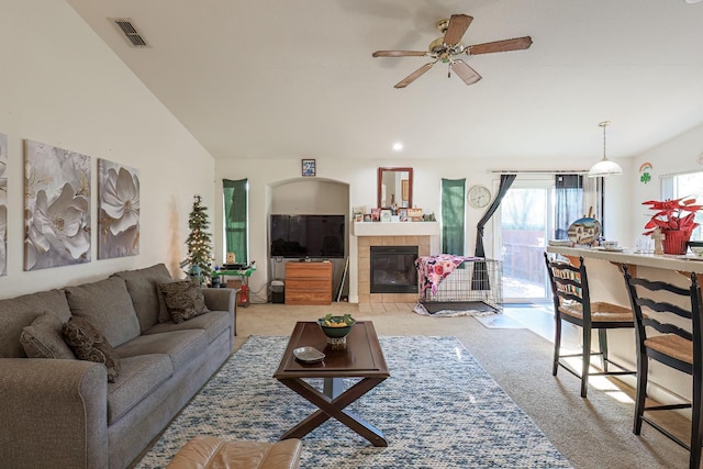 living room with ceiling fan, a tile fireplace, light carpet, and lofted ceiling