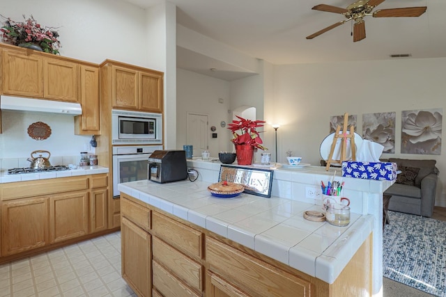 kitchen featuring white appliances, tile countertops, a center island, and ceiling fan