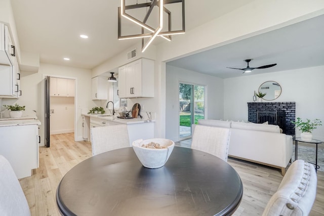 dining room featuring sink, ceiling fan, light hardwood / wood-style floors, and a fireplace