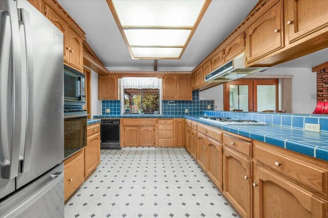 kitchen with decorative backsplash, sink, black appliances, and tile countertops