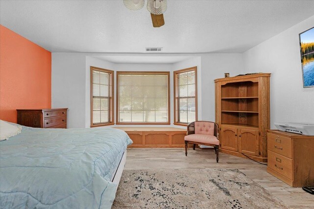 bedroom featuring ceiling fan, a textured ceiling, and light wood-type flooring