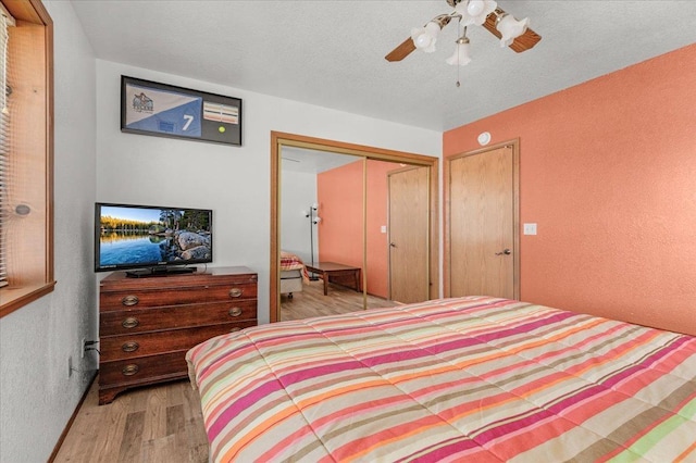 bedroom with a textured ceiling, light hardwood / wood-style flooring, a closet, and ceiling fan