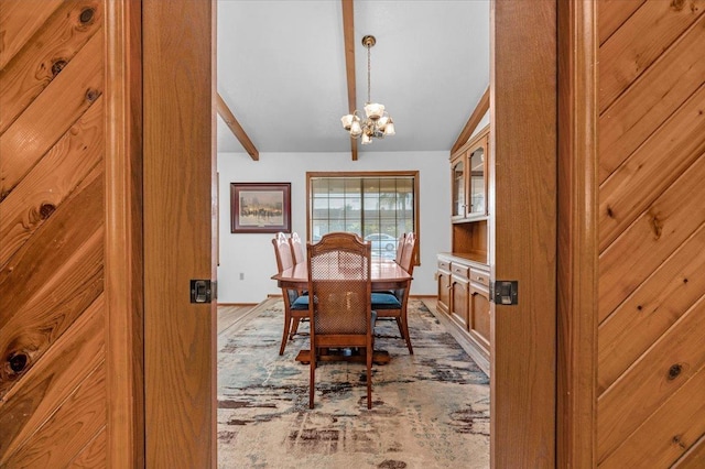 dining area featuring vaulted ceiling with beams and an inviting chandelier