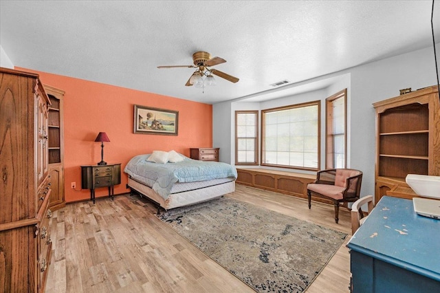 bedroom with ceiling fan, a textured ceiling, and light wood-type flooring