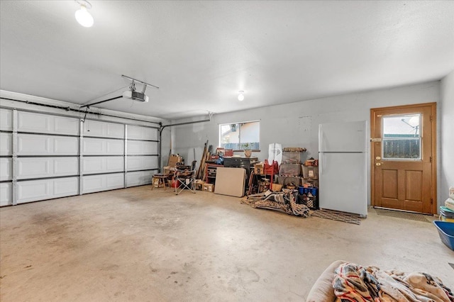 garage featuring white refrigerator and a garage door opener