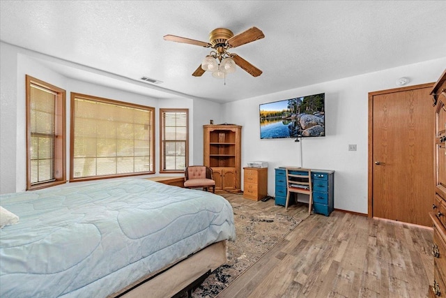 bedroom with a textured ceiling, light hardwood / wood-style flooring, and ceiling fan