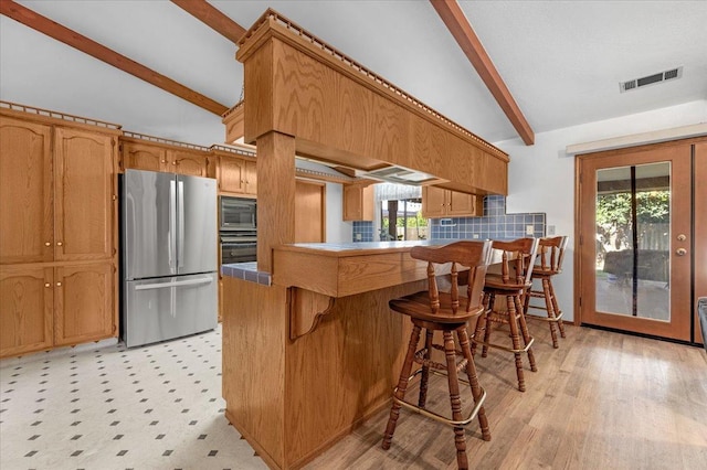 kitchen featuring stainless steel fridge, lofted ceiling with beams, kitchen peninsula, a breakfast bar area, and built in microwave