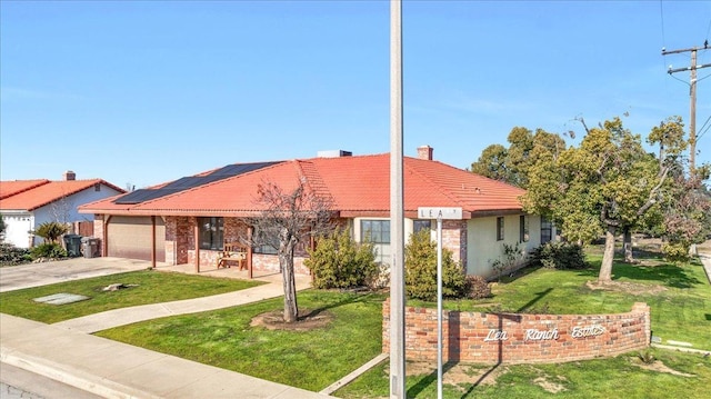 ranch-style home featuring a garage, a front yard, and solar panels