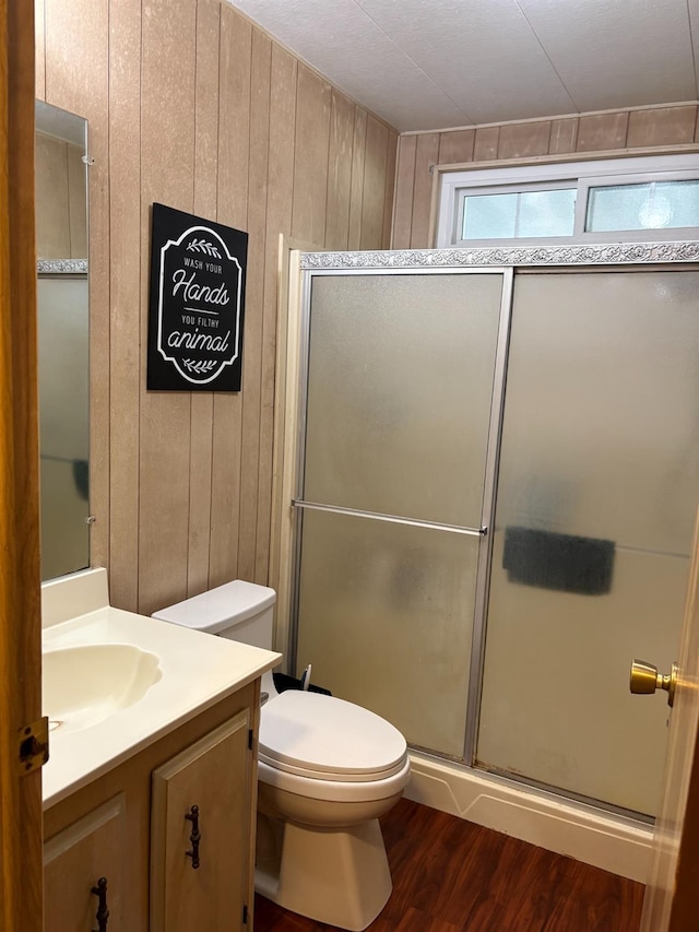 bathroom featuring vanity, toilet, walk in shower, wood walls, and hardwood / wood-style flooring