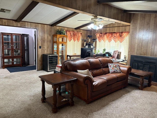 living room with wood walls, carpet flooring, beam ceiling, and ceiling fan