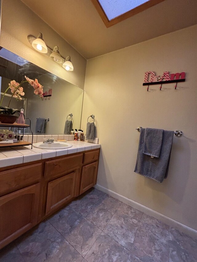 bathroom featuring a skylight, vanity, and baseboards