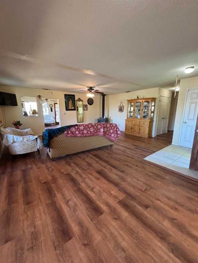 unfurnished bedroom with a textured ceiling, wood finished floors, and a wood stove