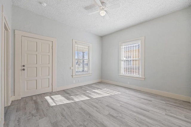 empty room with ceiling fan, a textured ceiling, and light wood-type flooring