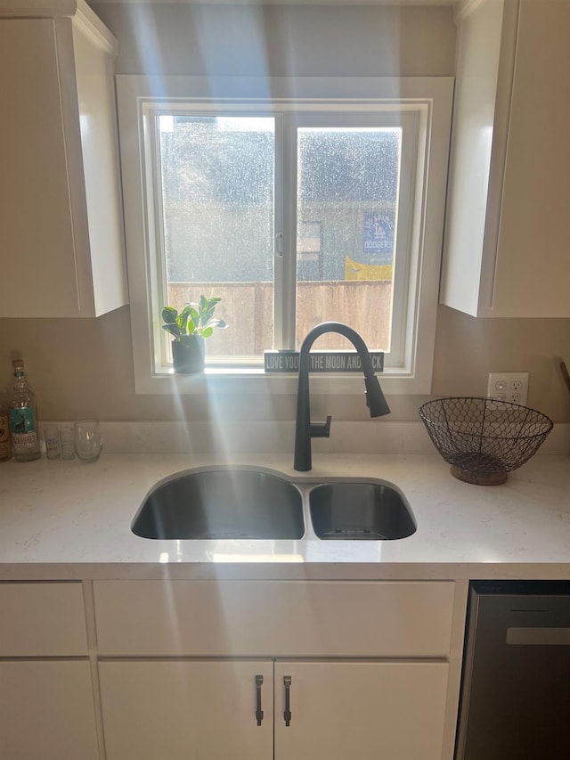 kitchen featuring white cabinets, light stone counters, and sink