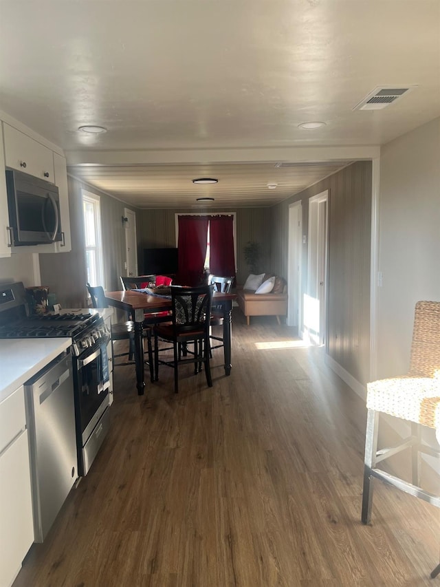 kitchen with white cabinets, appliances with stainless steel finishes, and dark hardwood / wood-style flooring