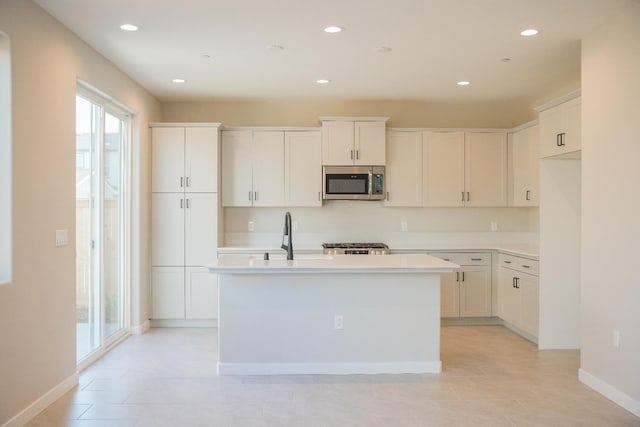 kitchen featuring sink, white cabinetry, a kitchen island with sink, and light tile patterned floors