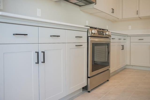 kitchen with light tile patterned flooring, white cabinetry, and stainless steel gas range oven