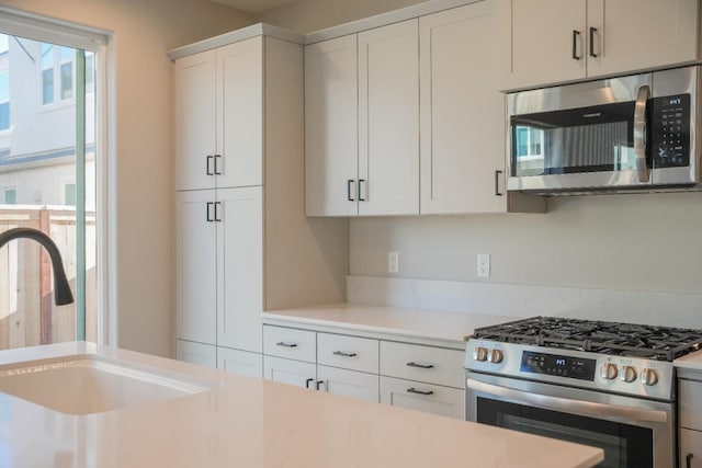 kitchen with sink, stainless steel appliances, and white cabinetry