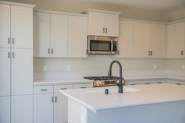 kitchen featuring white cabinets and an island with sink