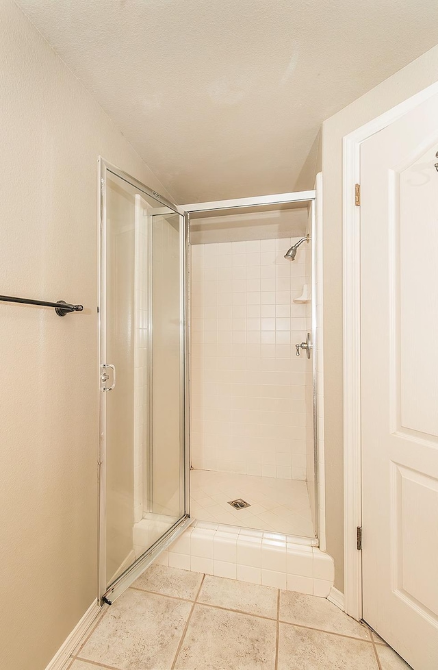 bathroom with tile patterned flooring, a shower with door, and lofted ceiling