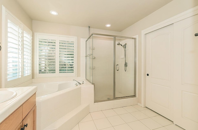 bathroom with tile patterned floors, plenty of natural light, plus walk in shower, and vanity