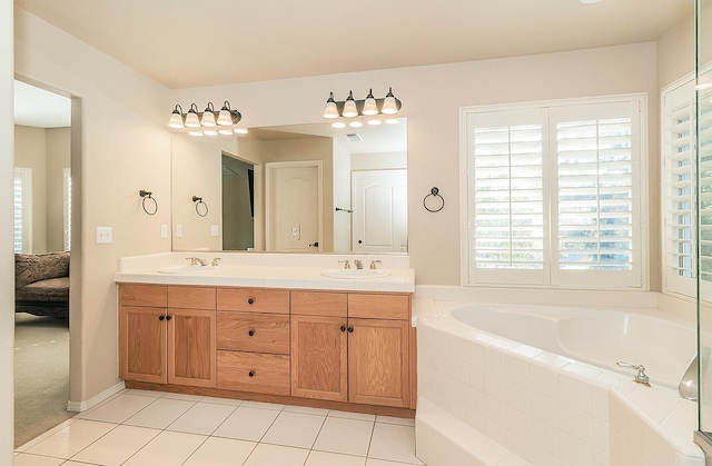 bathroom featuring tile patterned flooring, vanity, and tiled bath