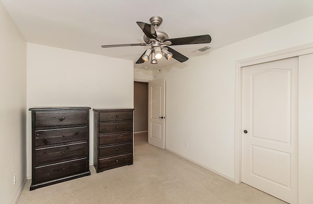 unfurnished bedroom featuring ceiling fan, light colored carpet, and a closet