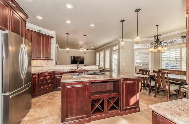 kitchen with a center island, ornamental molding, pendant lighting, stainless steel appliances, and backsplash