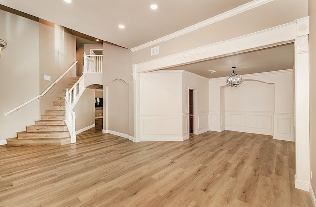 unfurnished living room featuring crown molding, light wood-type flooring, and a chandelier