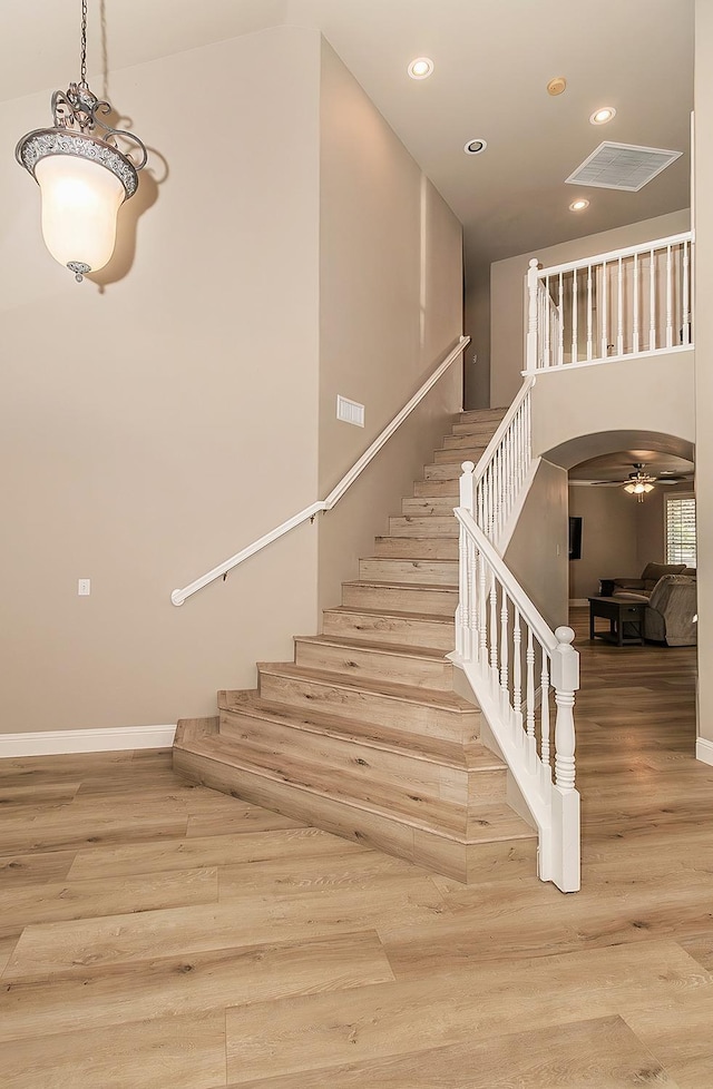 stairway featuring ceiling fan and hardwood / wood-style floors