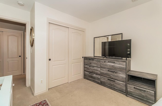 bedroom with light carpet and a closet