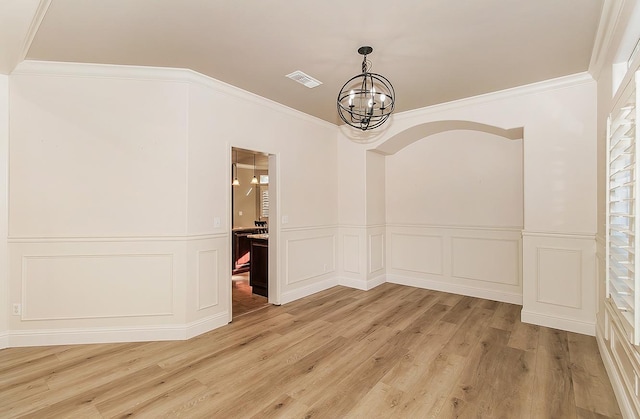 unfurnished dining area with crown molding, a notable chandelier, and light wood-type flooring