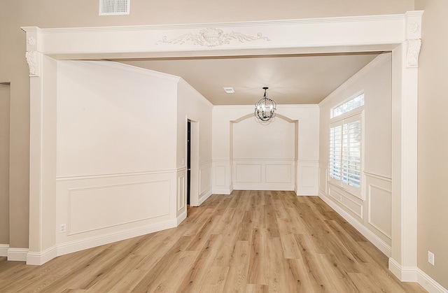 hall with a notable chandelier, ornamental molding, and light hardwood / wood-style floors