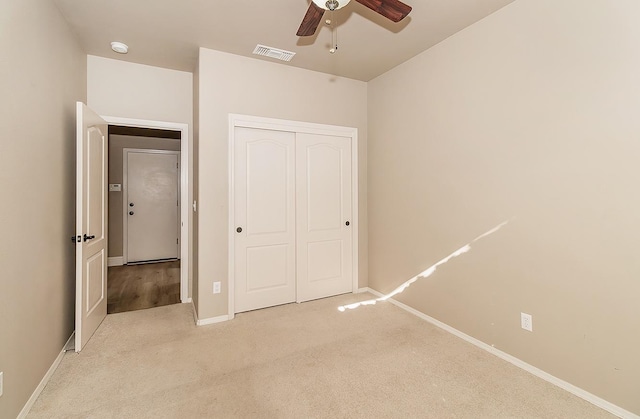 unfurnished bedroom featuring light colored carpet, ceiling fan, and a closet