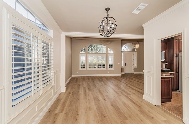 entryway with ornamental molding, light hardwood / wood-style flooring, and a notable chandelier