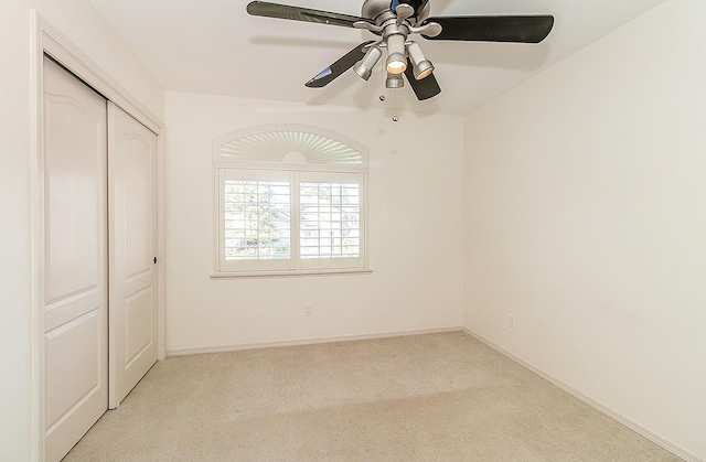 unfurnished bedroom with light colored carpet, a closet, and ceiling fan