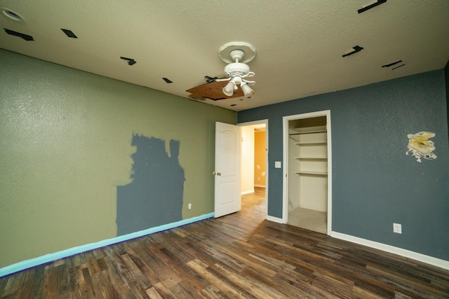 unfurnished bedroom with ceiling fan, a textured ceiling, dark hardwood / wood-style floors, and a closet