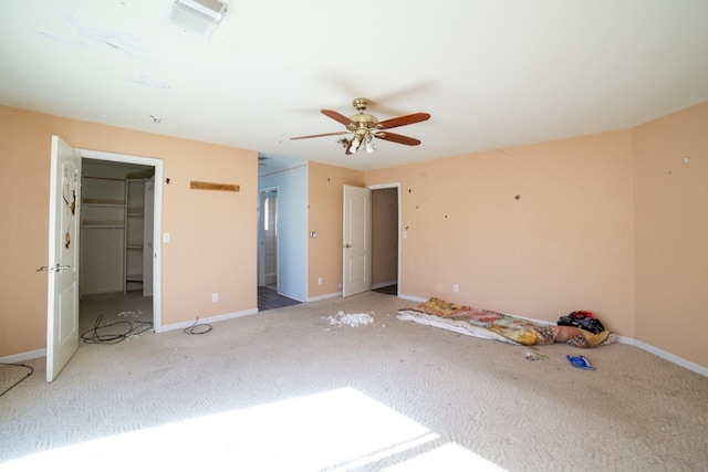 unfurnished bedroom with a walk in closet, ceiling fan, carpet floors, and a closet