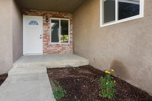 entrance to property featuring brick siding and stucco siding